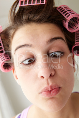 Teenage girl with hair in curlers pulling a face