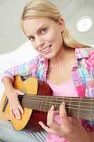 Teenage girl playing acoustic guitar