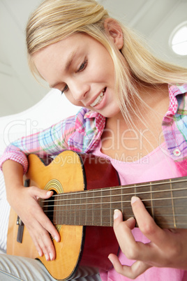 Teenage girl playing acoustic guitar