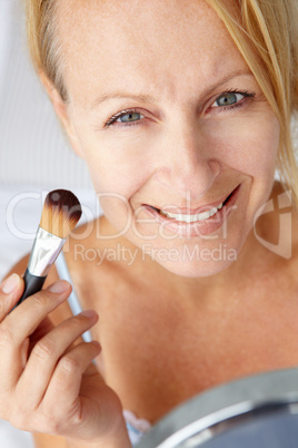 Mid age woman putting on make-up