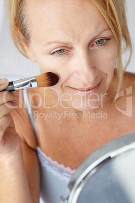 Mid age woman putting on make-up