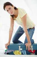 Woman struggling to close suitcase