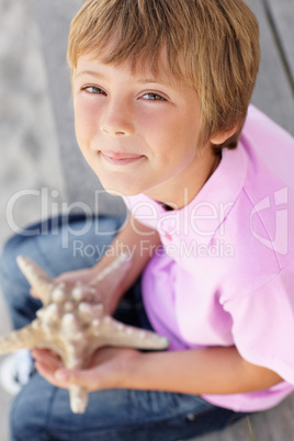 Young boy outdoors holding starfish