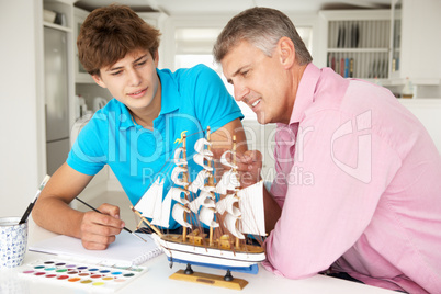 Father and teenage son model making and painting