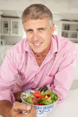 Mid age man eating salad