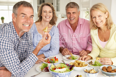 Mid age couples enjoying meal at home