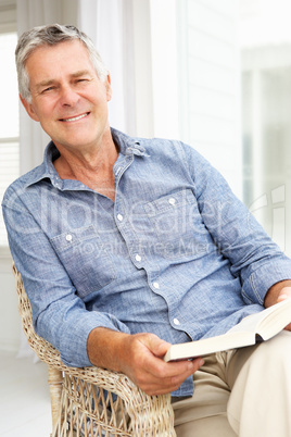 Senior man relaxing at home with a book