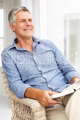 Senior man relaxing at home with a book