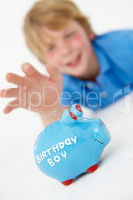 Young boy reaching for piggy bank