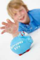 Young boy reaching for piggy bank