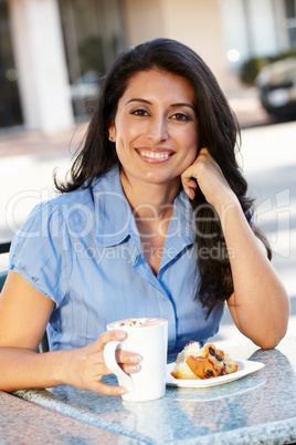 Hispanic woman sitting at sidewalk café