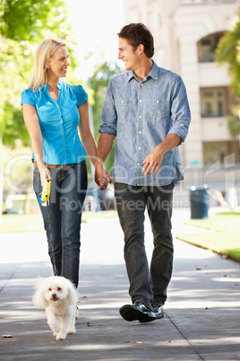 Couple walking with dog in city street
