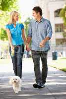Couple walking with dog in city street