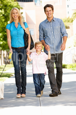 Family walking with dog in city street