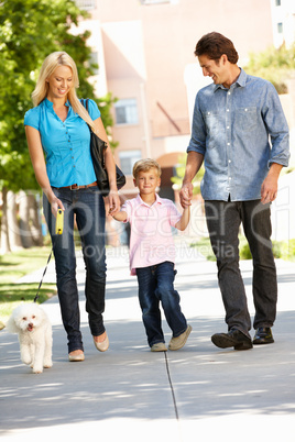 Family walking with dog in city street