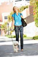 Woman walking with dog in city street