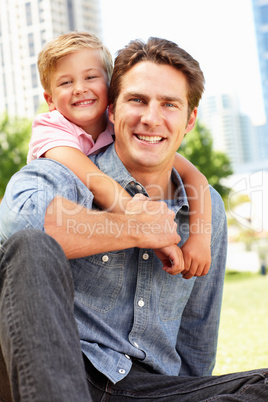 Man sitting in city park with young son