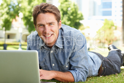 Man using laptop in city park