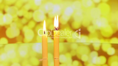 three candles rotating on reflective surface