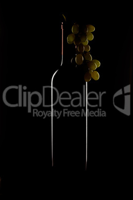bottle of wine and a bunch of grapes on a black background