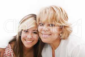 mother and attractive young daughter smiling happily, looking at