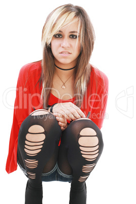 Young woman in punk attire bends over to hug her legs while look