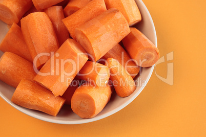 Fresh chopped carrots on an orange background