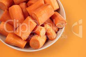 Fresh chopped carrots on an orange background