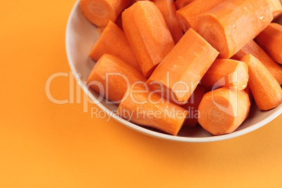 Fresh chopped carrots on an orange background