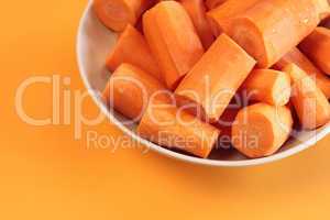 Fresh chopped carrots on an orange background