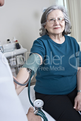 Doctor measuring mature patient blood presure