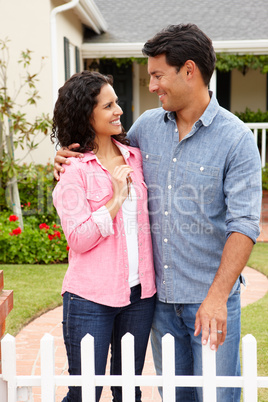 Hispanic couple outside new home