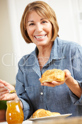 Mid age woman eating croissants