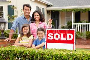 Hispanic family outside home with sold sign
