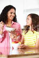 Mother and daughter eating cereal and fruit