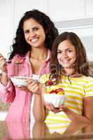 Mother and daughter eating cereal and fruit