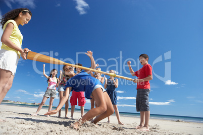 Teenagers doing limbo dance on beach