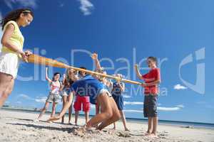 Teenagers doing limbo dance on beach