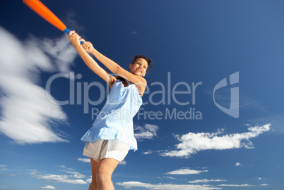 Teenage girl playing baseball on beach