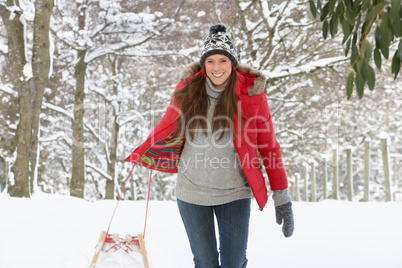 Young woman in snow with sledge