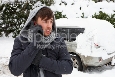 Young man in snow with broken down car