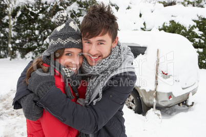 Young couple in snow with car