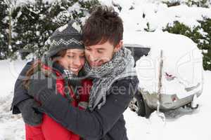Young couple in snow with car