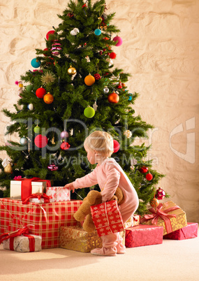 Little girl with parcels round Christmas tree