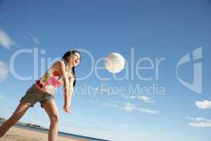 Teenage girl playing beach volleyball