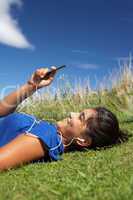 Teenage girl lying on grass with mp3 player