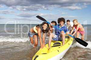 Teenagers in sea with canoe