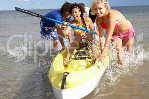 Teenagers in sea with canoe