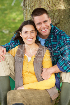 Couple sitting against tree trunk