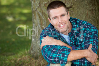 Man sitting against tree trunk